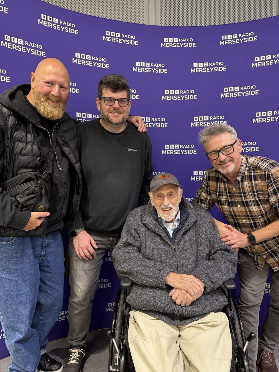 Mike Lowe in his wheelchair at BBC Radio Merseyside, with Rory Wilmer and two friends standing around him.